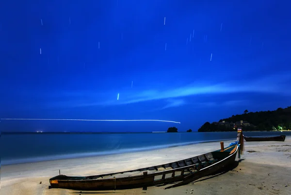 Um barco de pesca de madeira abandonado em uma praia de areia à noite — Fotografia de Stock