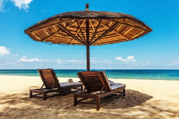 Cadeiras de madeira e guarda-chuvas na praia de areia branca — Fotografia de Stock