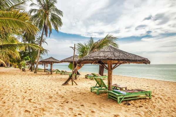 Wooden chairs and umbrellas on white sand beach — Stock Photo, Image