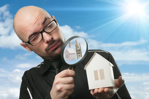 Man with a magnifying glass and paper house — Stock Photo, Image