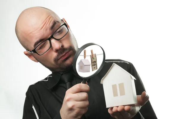 Man with a magnifying glass and paper house — Stock Photo, Image