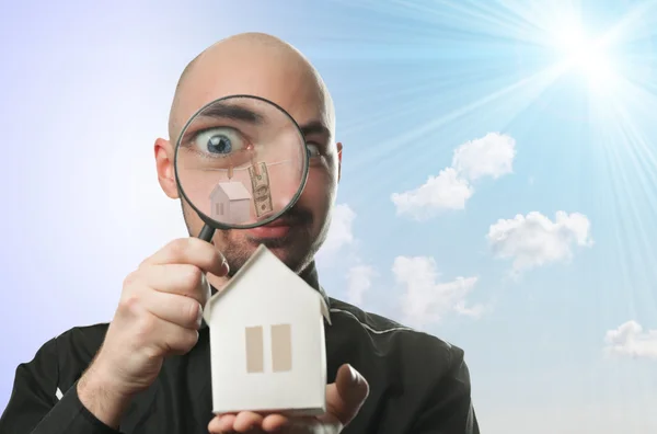 Man with a magnifying glass and paper house — Stock Photo, Image
