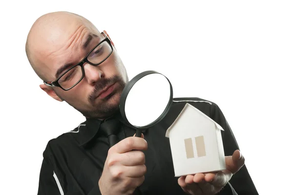 Man met een vergrootglas en papier huis Stockfoto