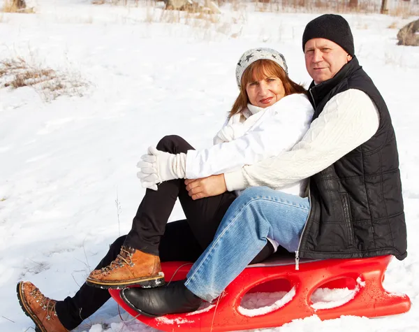 Mature couple sledding — Stock Photo, Image