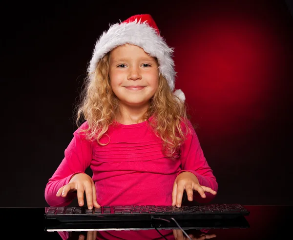 Girl in christmas hat with keybard — Stock Photo, Image