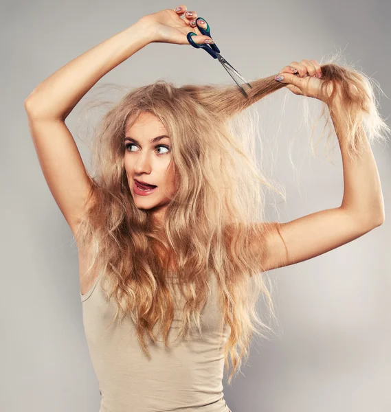 Ung kvinna tittar på kluvna hårtoppar — Stockfoto