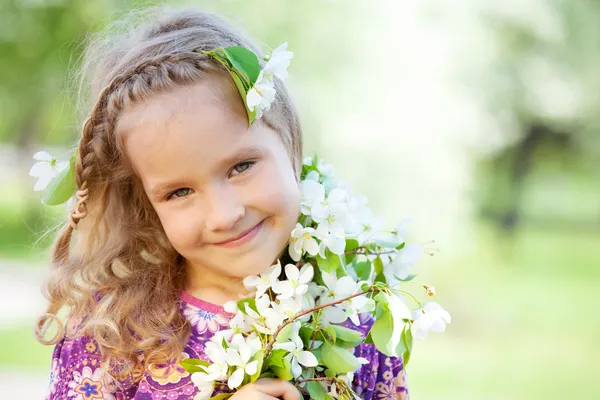 Liten flicka med grenar blommande äppelträd — Stockfoto