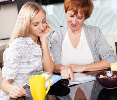 Mother and daughter read magazine at home clipart