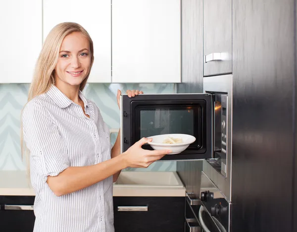 Frau wärmt Essen in der Mikrowelle auf — Stockfoto