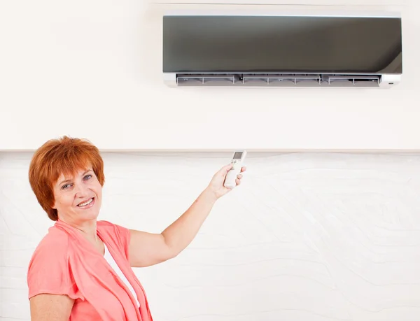 Frau in der Hand einer ferngesteuerten Klimaanlage — Stockfoto