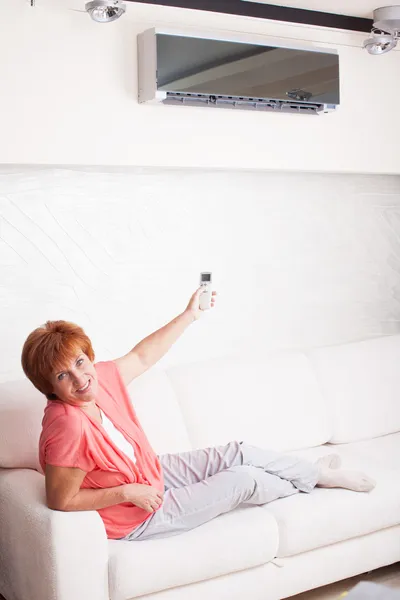 Mulher segurando um controle remoto ar condicionado — Fotografia de Stock