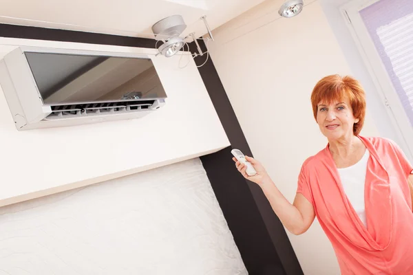 Woman holding a remote control air conditioner — Stock Photo, Image