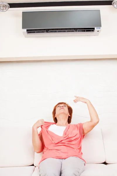Woman escapes from the heat under the air — Stock Image Woman escapes from the heat under the air Royalty Free Stock Images