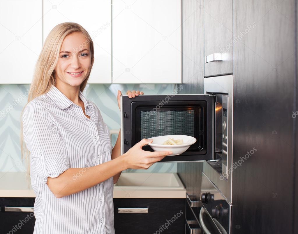 Woman warms up food in the microwave — Stock Photo © TatyanaGl 24713739