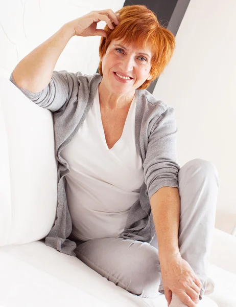 Gelukkig volwassen vrouw op sofa — Stockfoto