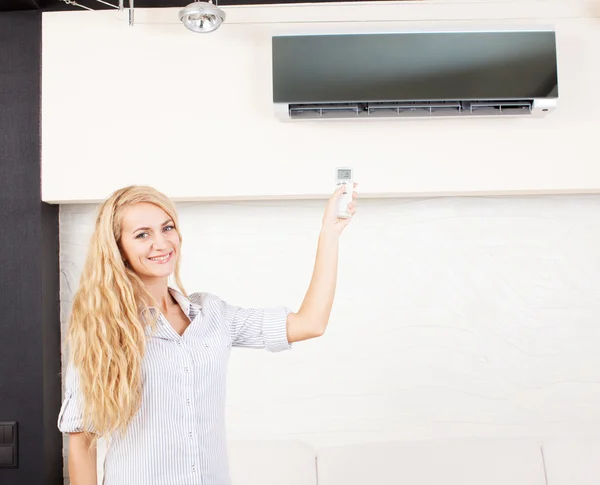 Frau in der Hand einer ferngesteuerten Klimaanlage — Stockfoto