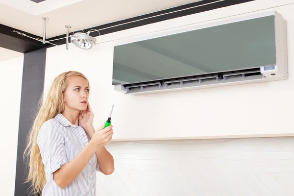 Woman looks at a broken air conditioner — Stock Photo, Image