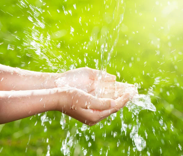 Strom sauberen Wassers ergießt sich in die Hände der Kinder — Stockfoto