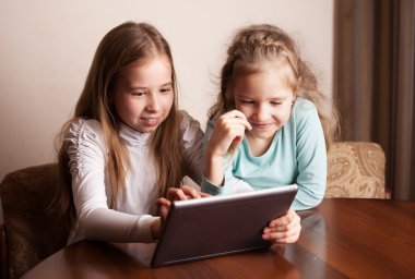 Tablet üzerinde oynayan çocuklar