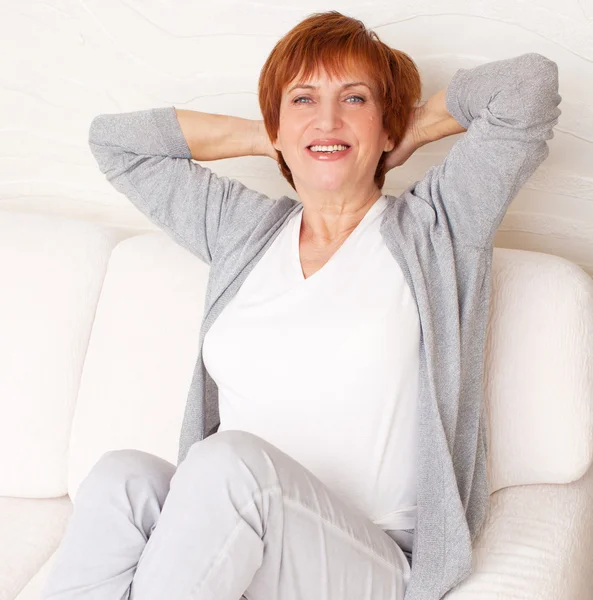 Gelukkig volwassen vrouw op sofa — Stockfoto