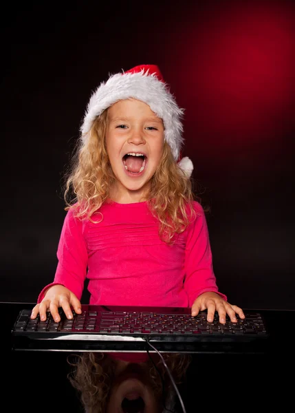 Happy girl in christmas hat with keybard — Stock Photo, Image