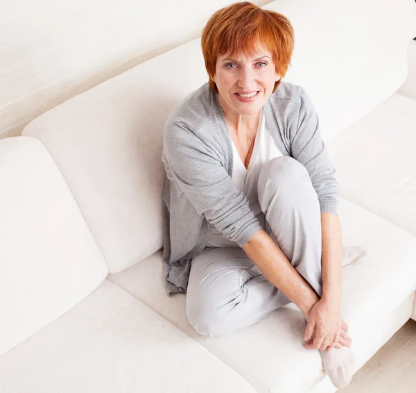 Gelukkig volwassen vrouw op sofa — Stockfoto