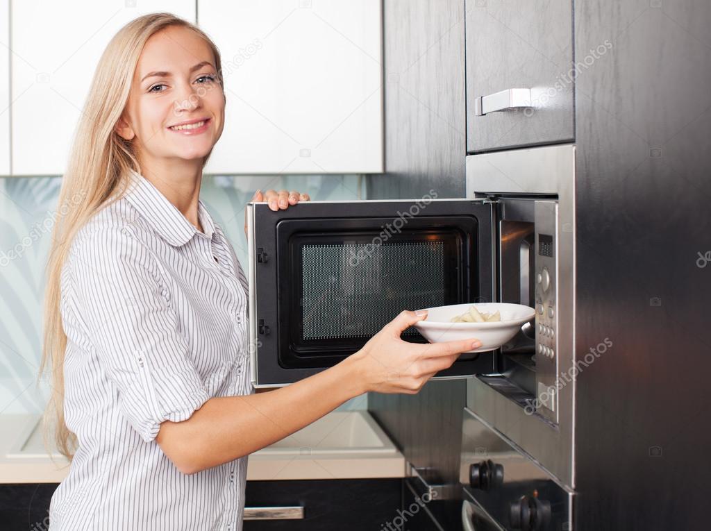 Woman warms up food in the microwave