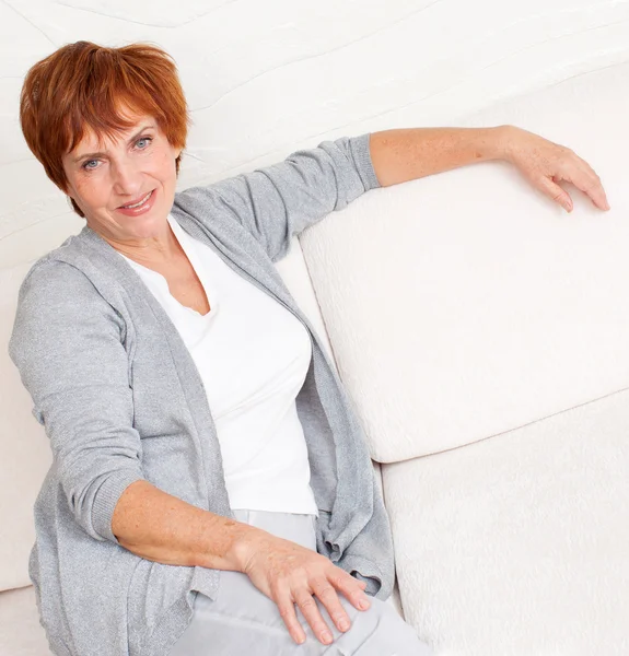 Gelukkig volwassen vrouw op sofa — Stockfoto