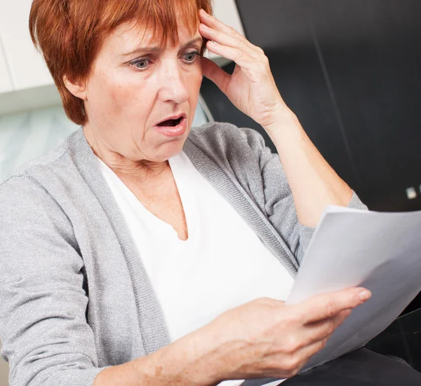 Oudere vrouw sorteren door middel van haar oude ontvangsten — Stockfoto