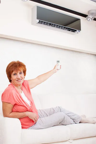 Mulher segurando um controle remoto ar condicionado — Fotografia de Stock