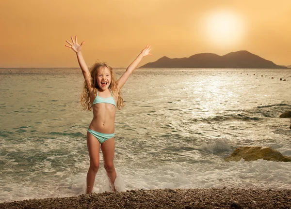 Meisje op het strand bij zonsondergang — Stockfoto