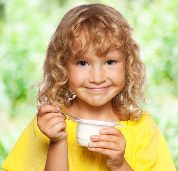 Little girl eating yogurt at summer — Stock Photo, Image