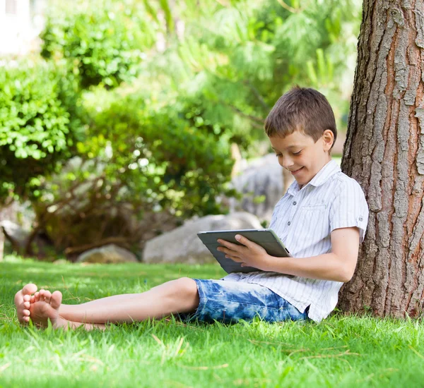 Jongen op gras met tablet pc — Stockfoto