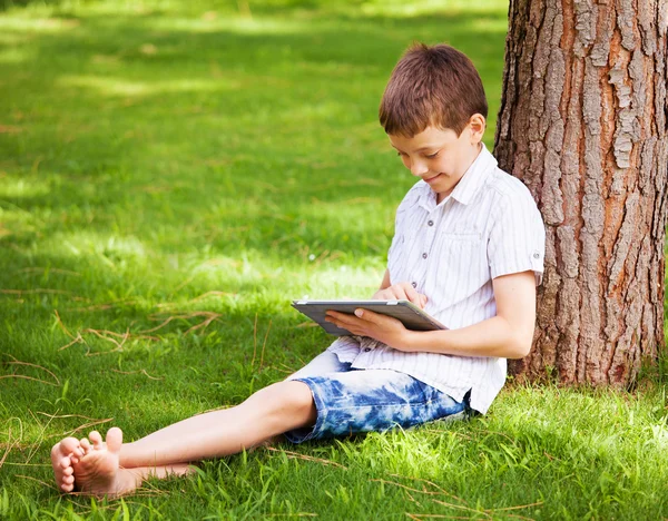 Tablet bilgisayar ile çimen çocuk — Stok fotoğraf