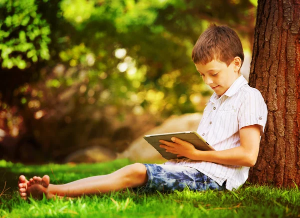 Niño en la hierba con la tableta — Foto de Stock