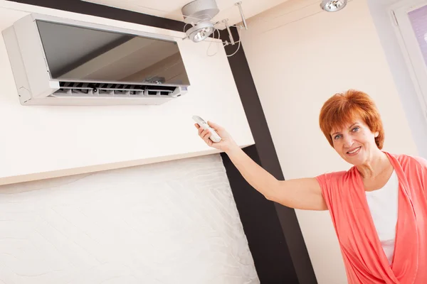 Frau in der Hand einer ferngesteuerten Klimaanlage — Stockfoto
