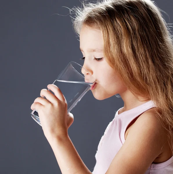 Flicka dricksvatten från glas — Stockfoto