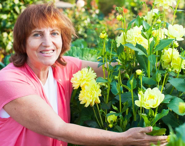 Kvinna i trädgården bryr sig för blommor — Stockfoto