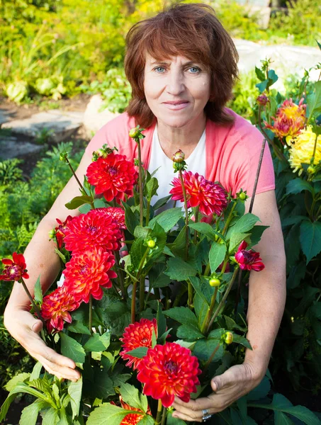 Женщина в саду ухаживает за цветами — стоковое фото