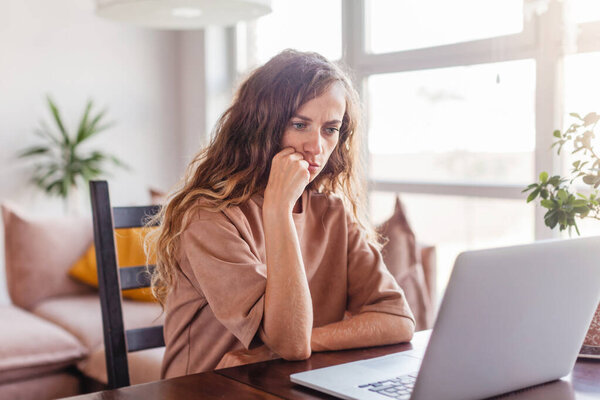 Frustrated Sad woman using laptop in living room