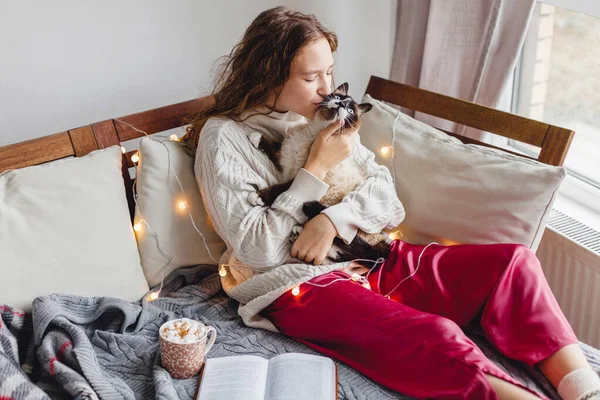 漂亮的年轻女人在和一只灰色的猫玩耍 小女孩坐在沙发上亲吻她的猫 — 图库照片