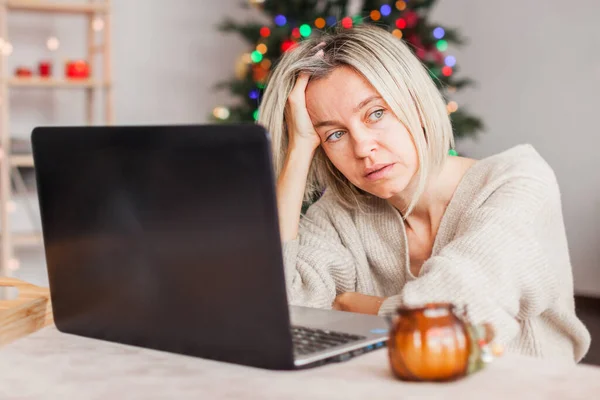 悲伤的成年女子在家中靠着圣诞树 一个女人因为必须在圣诞节工作而不快乐 — 图库照片