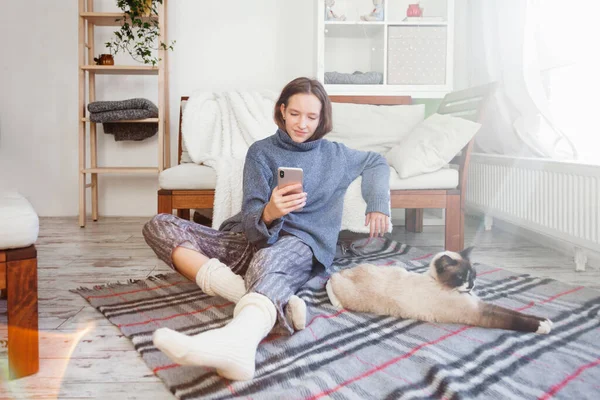 Girl Sitting Sofa Holding Phone Her Hands Warm Sweater Floor — Stock Photo, Image