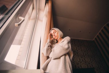disappointed sad lonely woman is sad at home by the window. Adult female has a lot of problems, is under stress