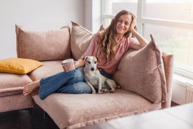 Sakin ve huzurlu orta yaşlı kadın bir ara veriyor, evdeki kanepede bir fincan sıcak çayla dinleniyor. Memnun, mutlu bir bayan kahve içiyor ve kanepede köpekle hayal kuruyor.