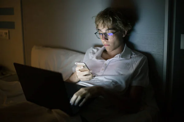 Young Man Lies Bed Open Laptop Mobile Phone Night Watching — Stock fotografie