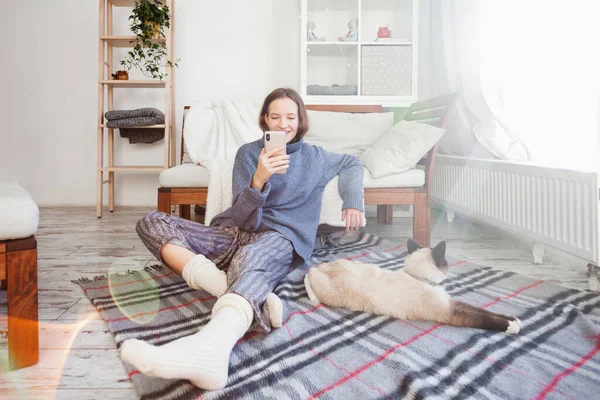 Mladá Žena Sedící Podlaze Držící Telefon Rukou Svetru Biue Usmívající — Stock fotografie