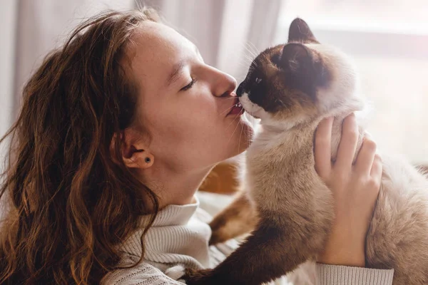 幸せな若いです女性接吻猫にホーム ロイヤリティフリーのストック写真