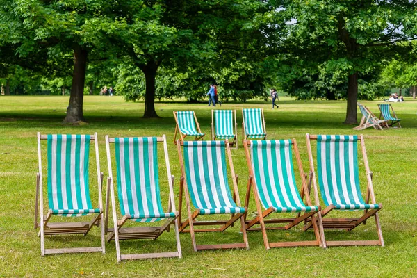 Yeşil parkta geleneksel çizgili güverte sandalyeleri. Londra, İngiltere