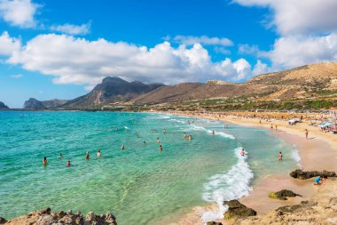 FALASSARNA, CRETE, GREECE - 20 Temmuz 2021: Resimli Falassarna plajında yüzen ve güneşlenen tatilciler